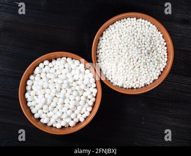 vista dall'alto della ciotola in ceramica con diverse palle di tapioca sago su tavolo di legno nero Foto Stock