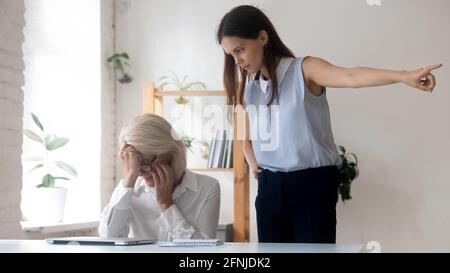 Le giovani donne d'affari arrabbiate sparano a una lavoratrice di mezza età Foto Stock