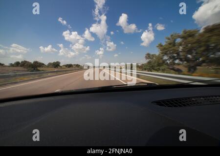 Guida una bella giornata di sole sulla strada di campagna locale di Estremadura, Spagna. Movimento sfocato all'interno della vista Foto Stock