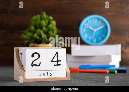 24 luglio. Luglio 24 calendario cubo di legno con oggetti sfocati sullo sfondo. Foto Stock