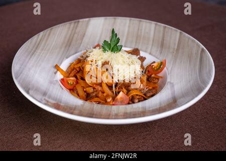 pasta appetitosa con manzo, pomodori e formaggi stagionati in un piatto Foto Stock