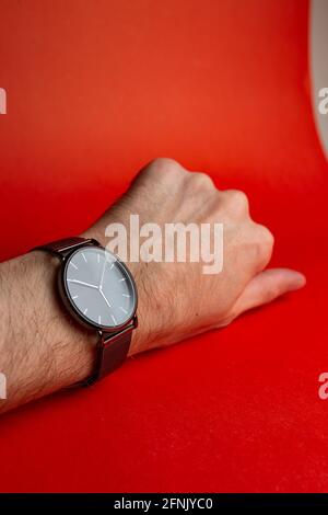 mano da uomo con orologio su sfondo rosso Foto Stock