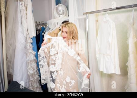 Una donna sceglie i vestiti in un atelier o in un deposito. Foto Stock