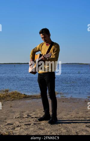 giovane che suona la chitarra in un pl selvaggio Foto Stock