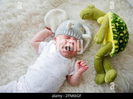 un neonato in un cappello divertente si posa e grida Foto Stock