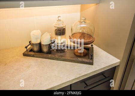 Vassoio di legno di oggetti decoratori su piano cucina Foto Stock