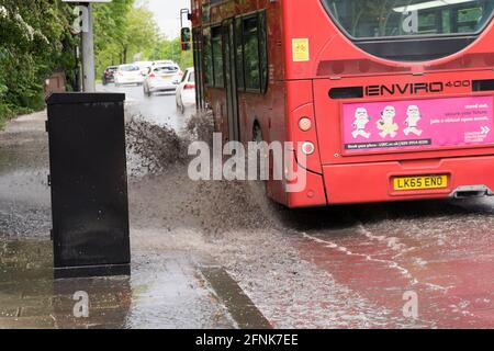 L'autobus Red london fa splash da un'inondazione di flash sulla circonvallazione sud, Greater London, England Foto Stock