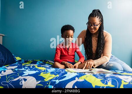 Madre che assiste il figlio che studia in camera da letto a casa Foto Stock