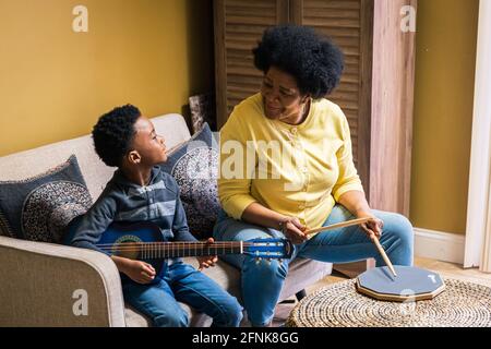 Donna anziana che suona la drum pad mentre nipote suona la chitarra a. casa Foto Stock