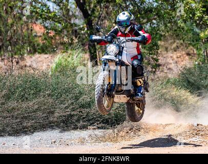 uomo che salta la sua moto di tipo scrambler sulla pista di sporcizia dentro Thailandia Foto Stock