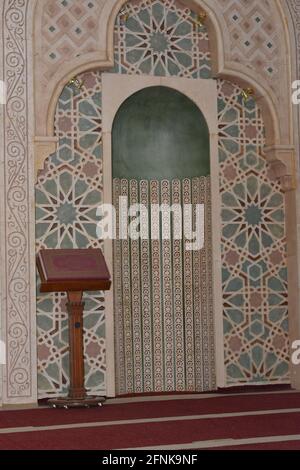 Una moschea dall'interno con uno stile decorativo islamico, la moschea Mihrab o una nicchia con un Corano messo su uno stand di legno Foto Stock