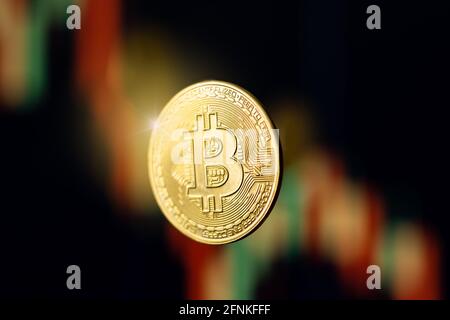 Moneta Bitcoin con luce svasata su grafico dei prezzi delle azioni sfocate Foto Stock