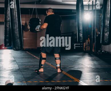 Silhouette boxer maschio di colpire un enorme sacco da boxe presso un studio di inscatolamento. Boxer uomo allenamento duro Foto Stock