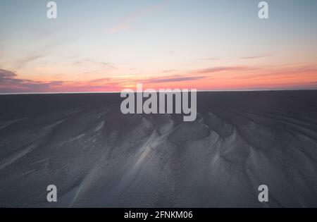 Bel tramonto dopo una giornata estiva, formazioni nella sabbia dopo le onde dall'oceano Foto Stock