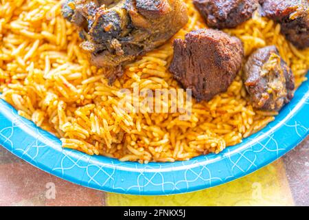 Riso nigeriano Jollof accompagnato da carne fritta Foto Stock