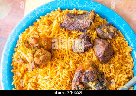 Riso nigeriano Jollof accompagnato da carne fritta Foto Stock