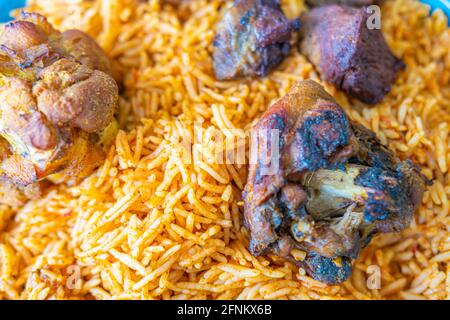 Riso nigeriano Jollof accompagnato da carne fritta Foto Stock