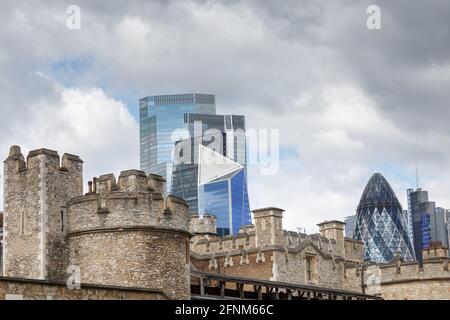 Uno skyline di Londra a contrasto dove offrono moderni grattacieli architettonici in vetro Un forte contrasto con la struttura in selce della Torre Di Londra Foto Stock