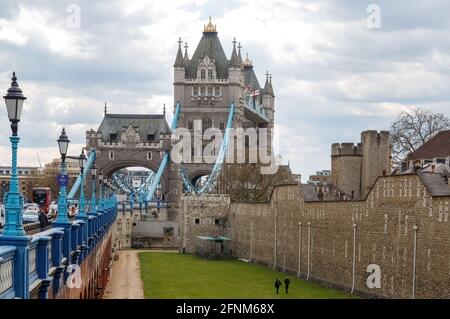 Una vista da Tower Bridge Piazza guardando verso Tower Bridge e la Torre di Londra, l'immagine incorniciata a sinistra da una serie di luci di strada in via di recedimento Foto Stock