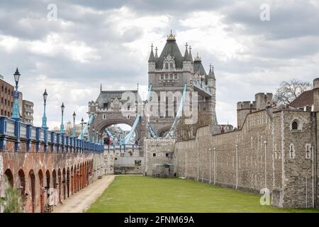Una vista da Tower Bridge Piazza guardando verso Tower Bridge e la Torre di Londra, l'immagine incorniciata a sinistra da una serie di luci di strada in via di recedimento Foto Stock