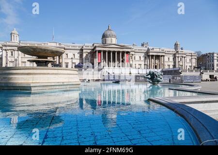 La Galleria Nazionale si riflette nelle acque blu ancora di una delle fontane di Piazza Trafalgar, che riempie l'immagine in primo piano. Foto Stock