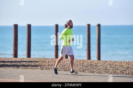 Brighton UK 18 maggio 2021 - UN corridore lungo il lungomare di Brighton su una bella mattina calda e soleggiata, ma il tempo più instabile è previsto per più tardi nel giorno in tutta la Gran Bretagna : Credit Simon Dack / Alamy Live News Foto Stock