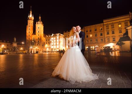 La notte è giovane. Messa a fuoco morbida foto a tutta lunghezza di una giovane coppia sposata felice abbracciando sulla piazza centrale della città Foto Stock