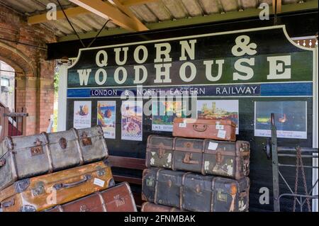 Sulla piattaforma a Quorn & Woodhouse Station, con segnaletica e vecchie valigie, Great Central Railway, Regno Unito Foto Stock