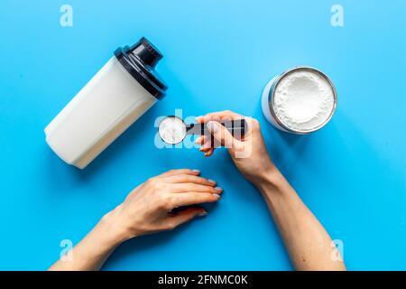 Mani che tengono polvere di proteina in paletta. Nutrizione sportiva Foto Stock
