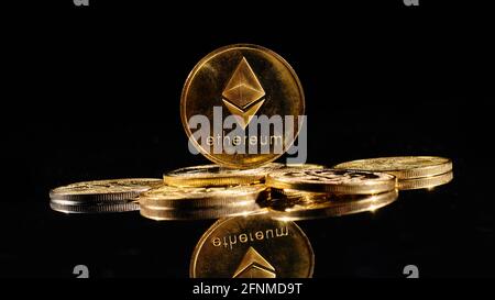 Monete d'oro da closeup con logo Ether. Nuova criptovaluta Ethereum ETH 2.0 su una cima di monete di bitcoin su sfondo nero. Un mucchio di decentralizzati Foto Stock