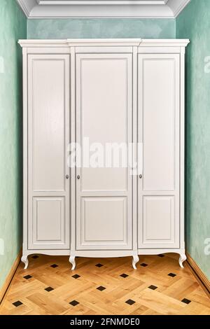 armadio bianco a tre sezioni in stile classico con gambe intagliate un corridoio moderno con pareti verdi ed elegante legno d'epoca pavimento in parquet Foto Stock