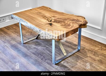 Moderno tavolo da caffè dal vivo con lastrina di olmo con nodo interno in bizzarra forma e anelli di alberi. Piano portapaziente su supporto in metallo Foto Stock