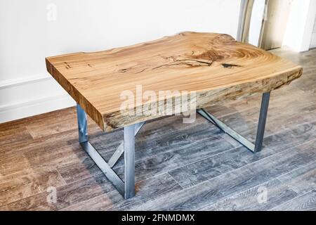 Moderno tavolo da caffè dal vivo con lastrina di olmo con nodo interno in bizzarra forma e anelli di alberi. Piano portapaziente su supporto in metallo Foto Stock