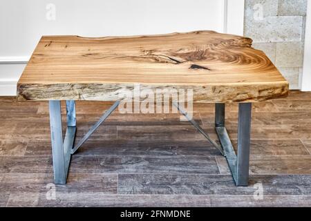 Moderno tavolo da caffè dal vivo con lastrina di olmo con nodo interno in bizzarra forma e anelli di alberi. Piano portapaziente su supporto in metallo Foto Stock