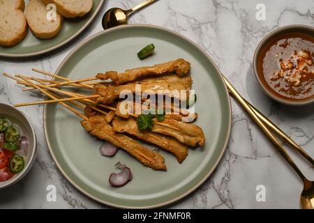 Vista dall'alto del tavolo da pranzo in marmo con satay di maiale grigliato (Moo Satay), salsa di arachidi e contorno Foto Stock