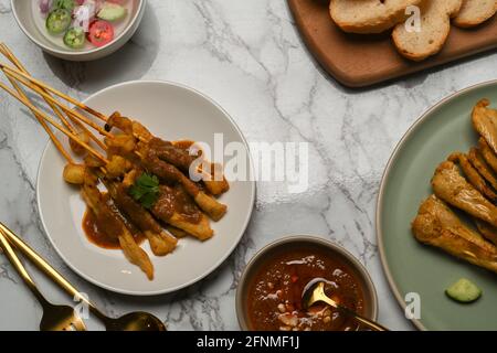 Vista dall'alto del satay di maiale grigliato (Moo Satay) con salsa di arachidi e contorno sul tavolo da pranzo in marmo Foto Stock