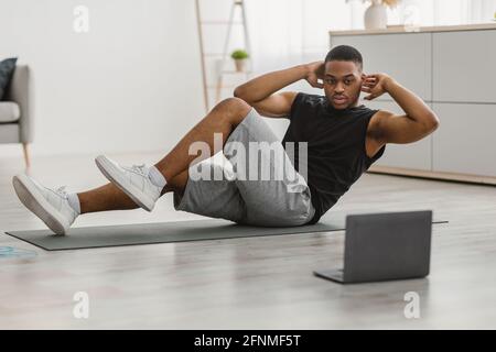 Guy africano facendo gomito a ginocchio ABS scricci a casa Foto Stock