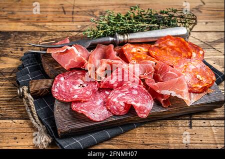 Piatto di salumi servito come tapas tradizionali spagnole. Salame, jamon, salsicce choriso su tavola di legno. Sfondo di legno. Vista dall'alto Foto Stock