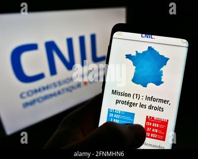 Persona titolare del cellulare con la pagina web dell'organismo di regolamentazione francese CNIL (privacy dei dati) sullo schermo davanti al logo. Mettere a fuoco il centro del display del telefono. Foto Stock