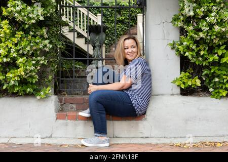 Una sola donna nel suo 40's seduto fuori a Savannah, Georgia in primavera guardando via Foto Stock