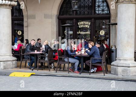 I turisti e i residenti locali godono di cibo e bevande sotto gli archi di ristoranti e bar nella piazza centrale del mercato della Città Vecchia di Cracovia, in Polonia Foto Stock