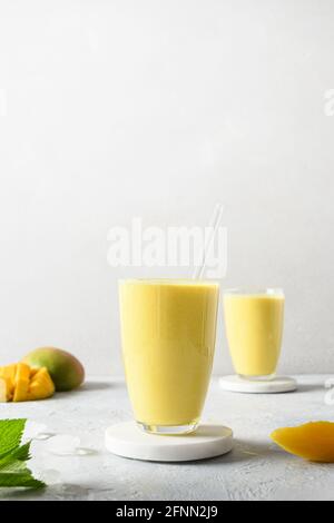 Lassie ayurvediche indiane di mango o lassi su sfondo grigio chiaro. Formato verticale. Lassie Mango bevanda sana tradizionale con yogurt, acqua, spezie Foto Stock