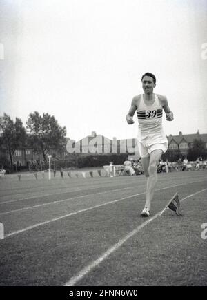 1954, storico, un concorrente maschile fuori correre su una pista di erba in una giornata di sport di servizio civile, Inghilterra, Regno Unito, un evento sportivo dilettante ma comunque competitivo. Foto Stock