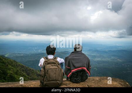 Uomini che guardano l'orizzonte del cielo blu dalla cima della collina e che sperimentano la natura. L'immagine è presa dall'anlge superiore a illikallu kerala. Foto Stock