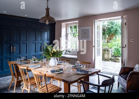 Sala da pranzo con armadi in ringhiere e pareti in terra rosa e aperto al giardino, Somerset. Foto Stock
