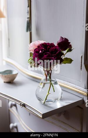Tre rose tagliate in vaso di vetro in cottage vittoriano del 19 ° secolo. Foto Stock
