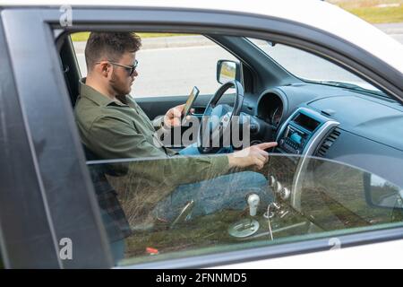 uomo seduto in auto utilizzando il telefono stile di vita distratto Foto Stock