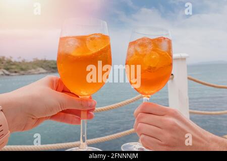 Due mani che tengono le bevande sul mare Foto Stock