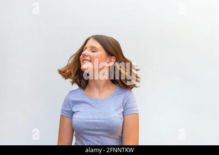 Ritratto di bella ragazzina caucasica con capelli volanti sorridenti ridendo relax su sfondo bianco Foto Stock