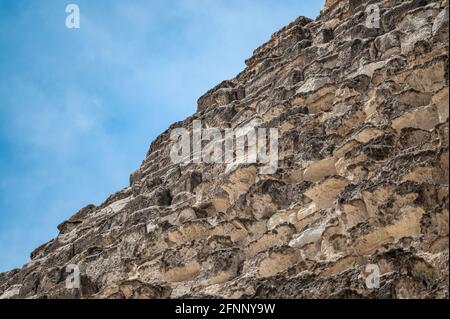 Antichi blocchi di pietra, parte della grande piramide, il volto della piramide di Cheope. Antichi blocchi di pietra contro il cielo blu. Grande Piramide di Giza. Foto Stock